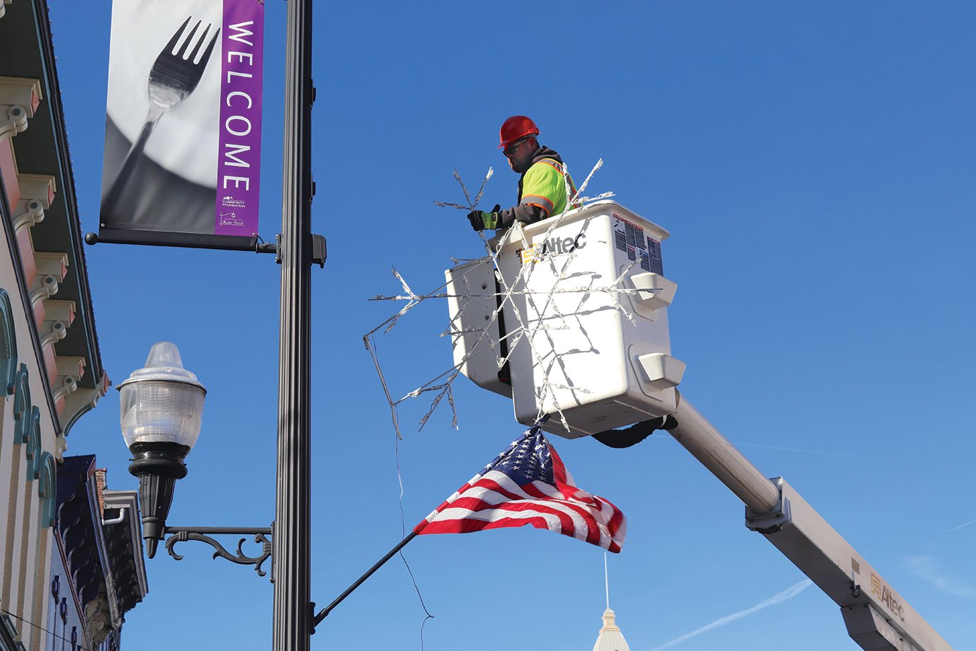 A Street Department bucket truck hoists worker Tom Edwards and a decorative snowflake above Main Street Tuesday morning.